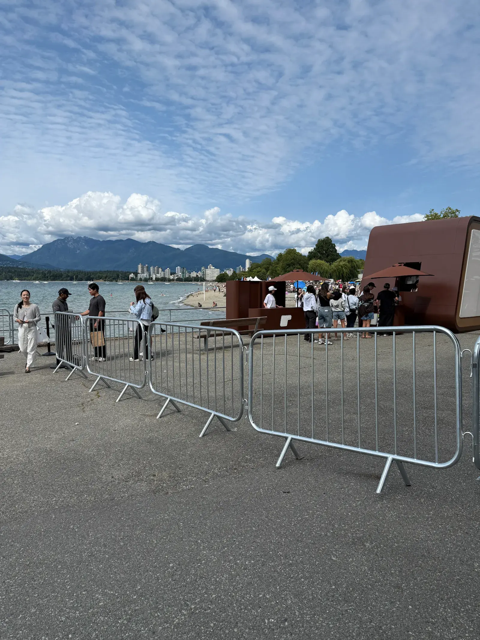 Steel barriers forming a line along a pathway at an outdoor waterfront event.