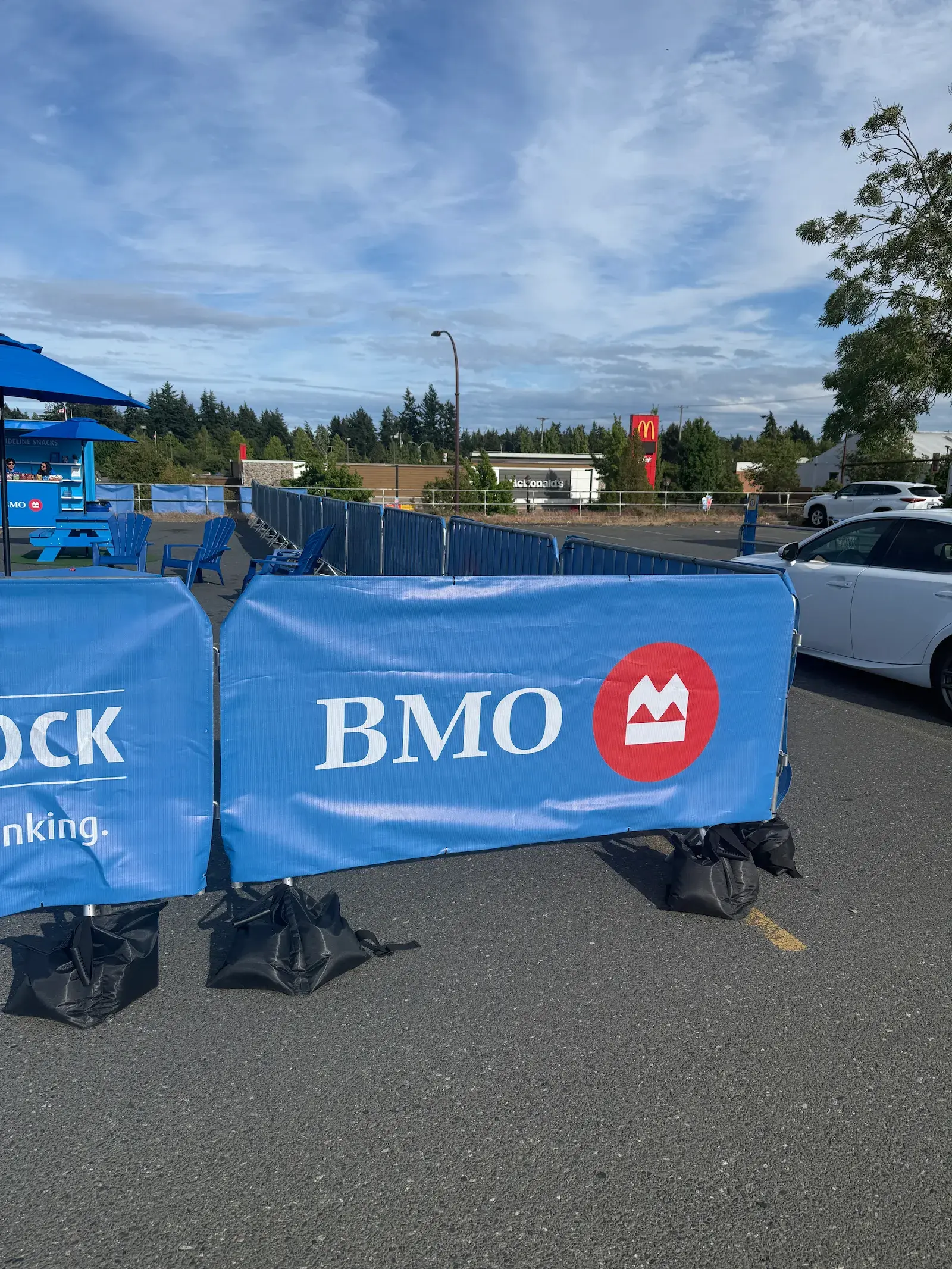 Steel barricades wrapped in event branding forming a perimeter in a parking lot.