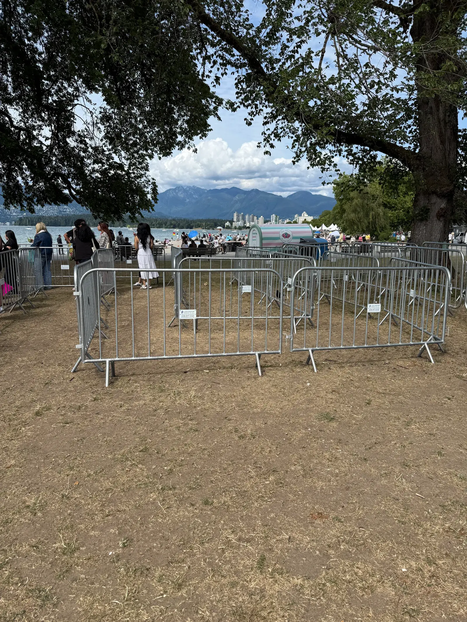 Steel barriers forming a queue enclosure at a busy outdoor event.